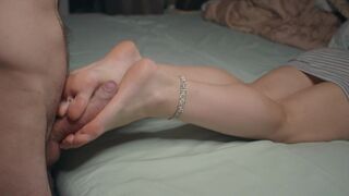A petite girl shows her small feet and performs a footjob, finishing with a cum shot on her soles