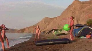 A barefoot girl plays badminton without clothes on the beach