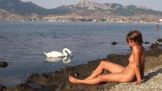 A hot naked girl is having fun on the riverbank