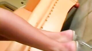 A cute beauty caresses herself in a leather chair, feeling great pleasure