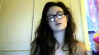A cute girl in glasses removes her clothes during a video chat