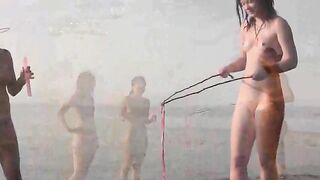 A naked girl is having fun on the beach in public