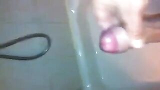 The kid caresses his dick under the jet of water in the shower