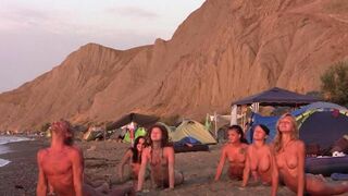 A group of naked people play volleyball on the beach in HD