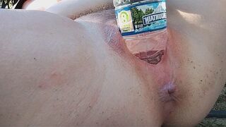 A woman reached the peak of pleasure while indulging in outdoor play with a water bottle